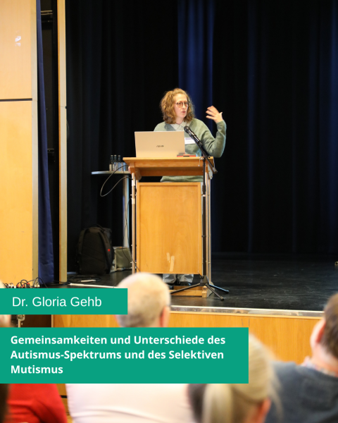 Eine Person steht hinter einem Rednerpult auf einer Bühne. Sie gestikuliert mit einer Hand. Auf grünem Hintergrund steht in weißer Schrift: „Dr. Gloria Gehb. Gemeinsamkeiten und Unterschiede des Autismus-Spektrums und des Selektiven Mutismus.“