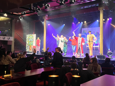 Auf der Bühne im GOP stehen mehrere verkleidete Personen, die ins Publikum winken. Darunter unter anderem der König, Lukas, der Lokomotivführer und Jim Knopf. Im Publikum sitzen mehrere Kinder und Erwachsene. Einige winken den Personen auf der Bühne zurück.